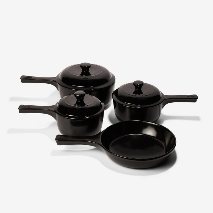 A set of Xtrema ceramic cookware in a sleek black finish. The set includes two covered saucepans of different sizes, one covered pot, and one open frying pan, all with a smooth design. The image emphasizes the durability and style of ceramic versus stainless steel cookware.


