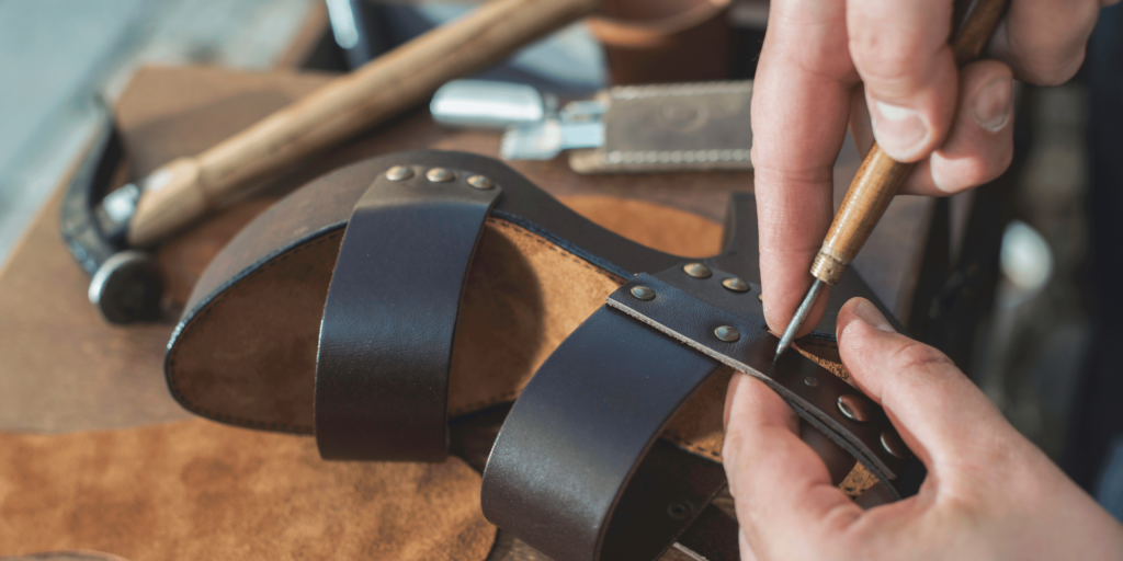 Artisan handcrafting a durable leather strap, showcasing traditional shoe repair tools, embodying the meticulous process of creating and maintaining sustainable, repairable footwear.