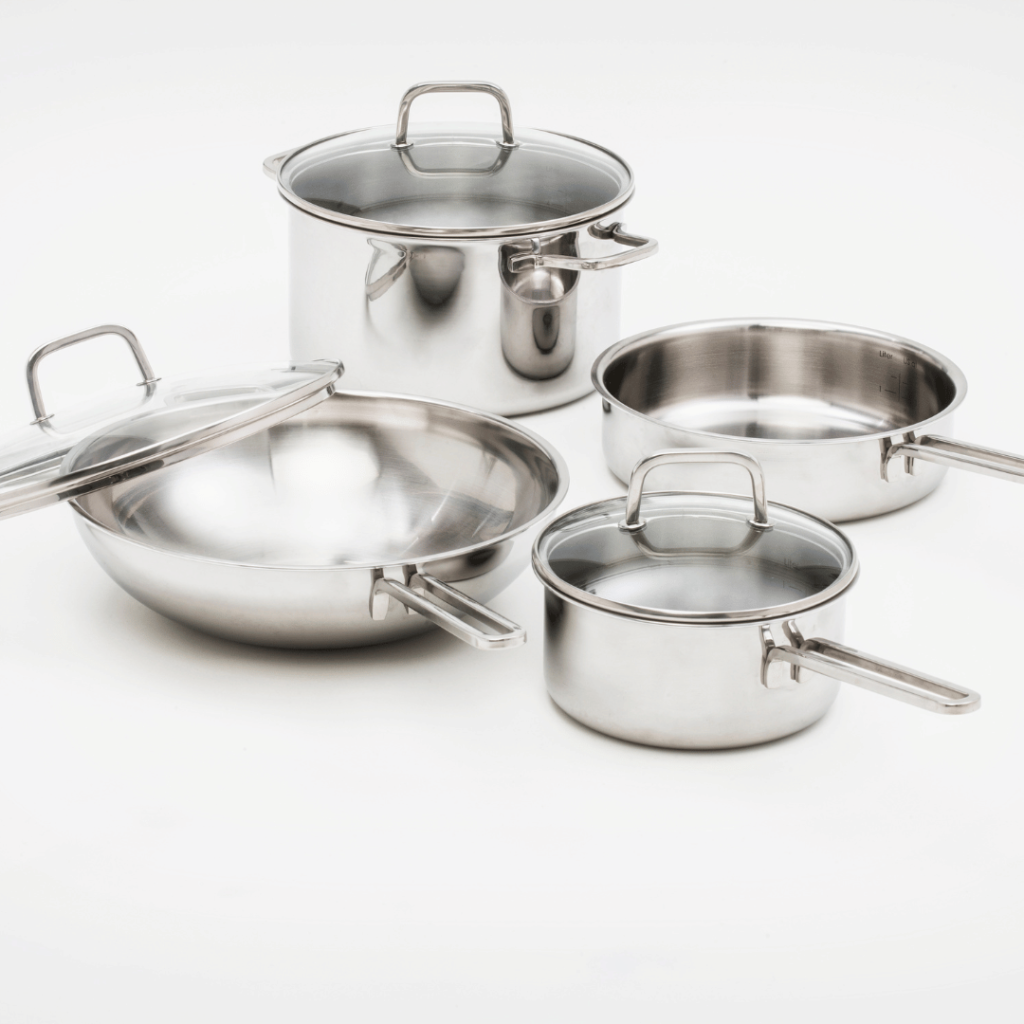 A set of gleaming stainless steel cookware on a white background. The set includes two saucepans with lids, a larger pot with lid, and an open frying pan, all with matching metallic handles. The reflective surfaces of the cookware showcase their clean lines and durable construction, ideal for a variety of cooking tasks.